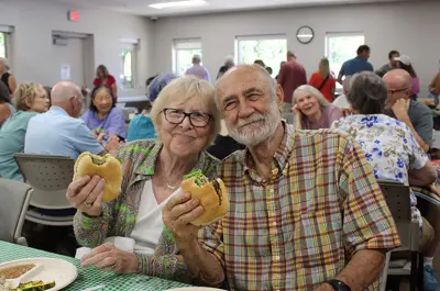 two seniors eating hamburgers at a special event hosted by the Brooks Cafe