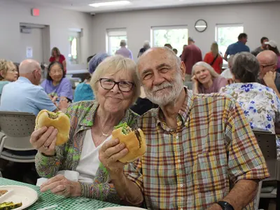 two seniors eating hamburgers at a special event hosted by the Brooks Cafe
