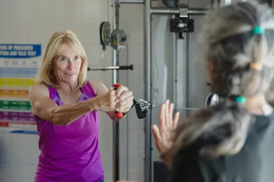Fitness instructor guiding an older adult through an exercise.