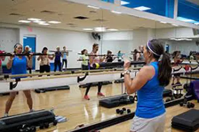 Instructor leading a group exercise class in a fitness studio.