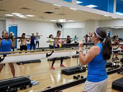 Instructor leading a group exercise class in a fitness studio.