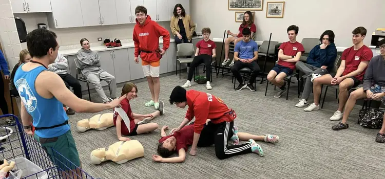Instructor demonstrating CPR to a seated training group.