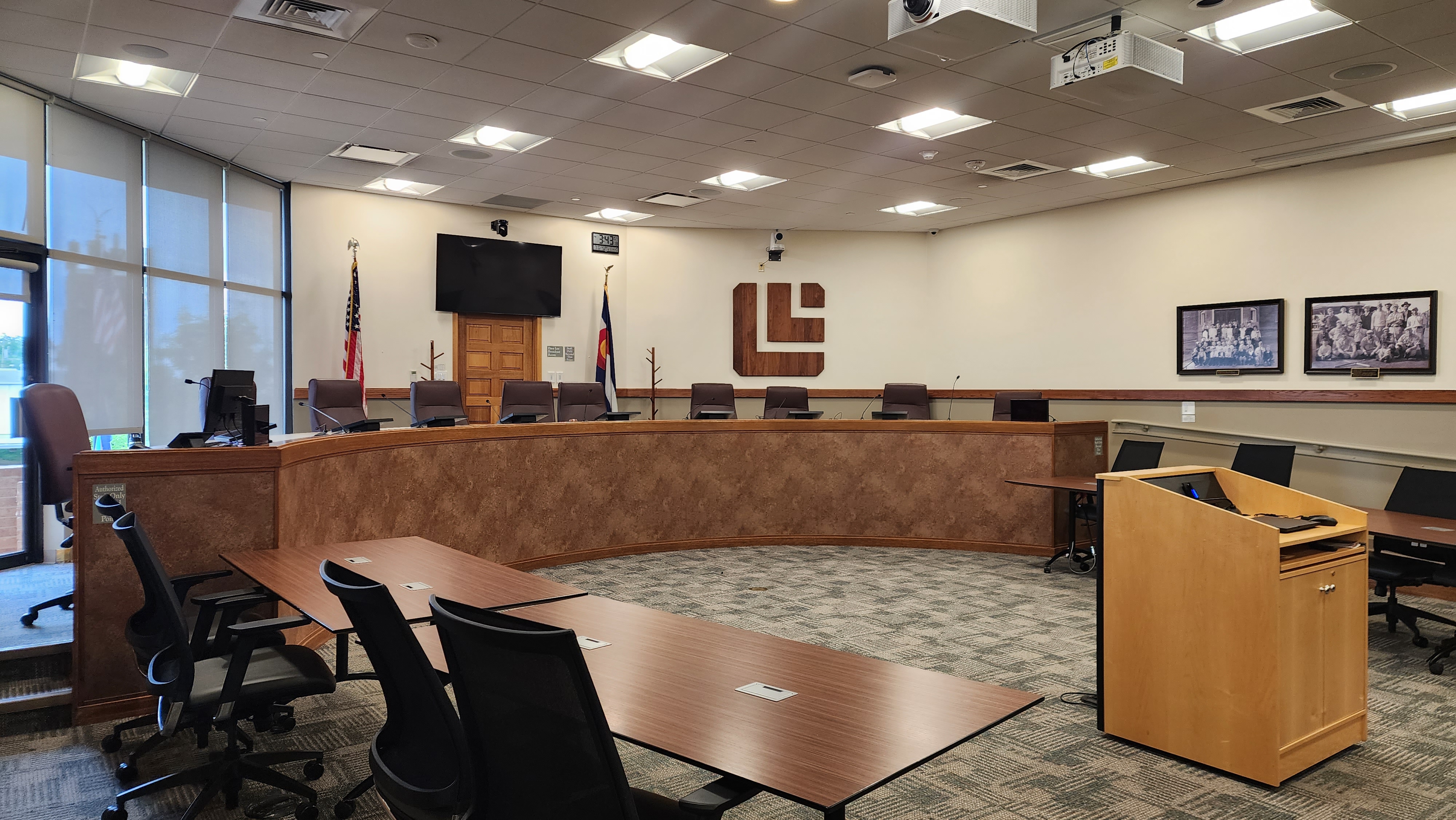 City Council chamber showing a rounded desk, chairs, and Louisville logo.