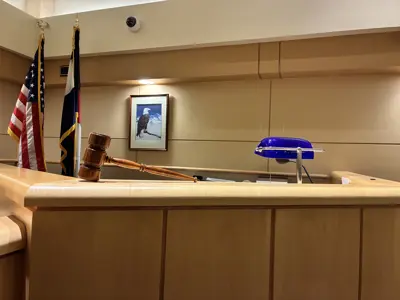 A gavel sitting on a desk with flags in the background.