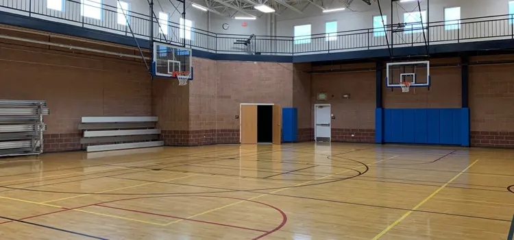 Indoor gymnasium with basketball hoops, bleachers, and court markings