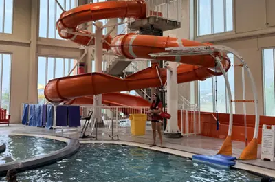 Twisting indoor water slides beside a shallow pool.