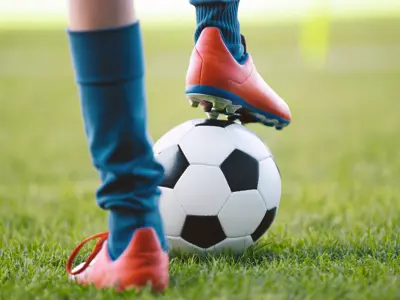 Soccer player standing with one foot on a ball.