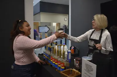 A volunteer handing a latte to a patron