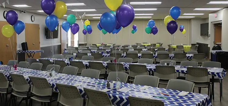 Event room decorated with colorful balloons and patterned tablecloths.