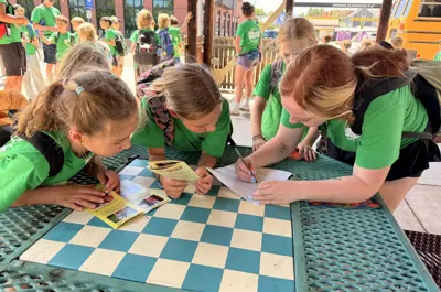 Summer Day Campers work together on a scavenger hunt at an outdoor table.