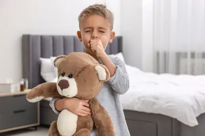 Child hugs a teddy bear while looking sick.